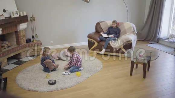 三个不同年龄的白种人儿童周末坐在家中壁炉前的长镜头年幼的孩子视频的预览图