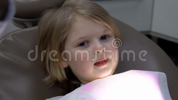 小女孩坐在一张特殊的椅子上对着牙医微笑视频的预览图