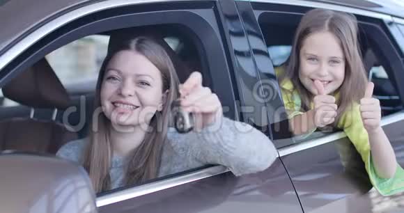 年轻的白人女人吹嘘汽车钥匙小女孩从汽车上竖起大拇指富有的商人买新衣服视频的预览图