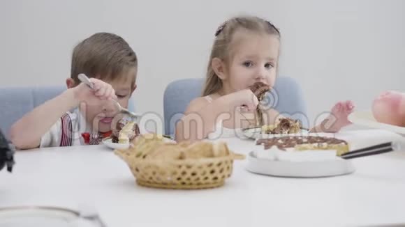 可爱的白种人男孩和女孩吃蛋糕的特写脸弟弟妹妹在生日那天吃甜食视频的预览图