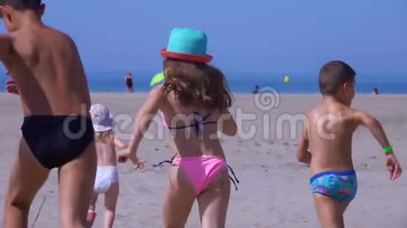 五个穿着鲜艳衣服的孩子在沙滩上奔向大海视频的预览图