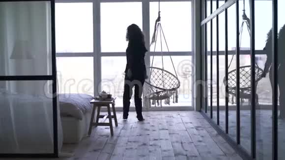 开朗的白种人女人在卧室的大窗户前跳舞和旋转从正面的黑发女孩的背面看视频的预览图