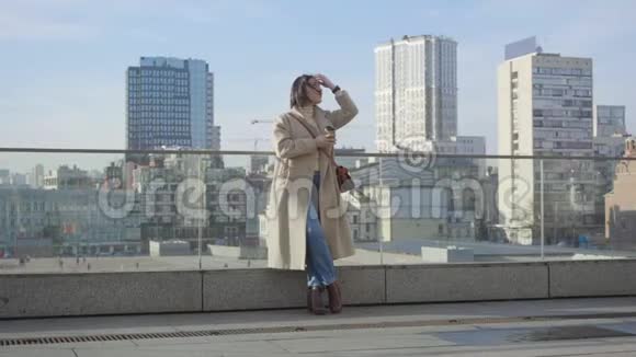 年轻的白种人商人站在城市里拿着咖啡杯看着远方自信的黑发女人优雅视频的预览图
