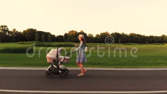 快乐的女人带着婴儿车在公园里散步视频的预览图