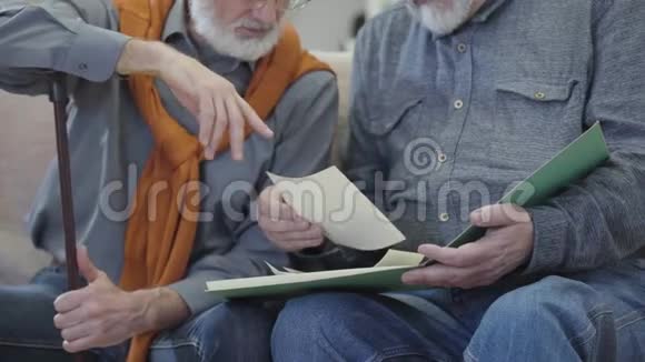 两个面目全非的白人男人看着老照片男人白发苍苍的退休者在室内回忆往事怀旧视频的预览图