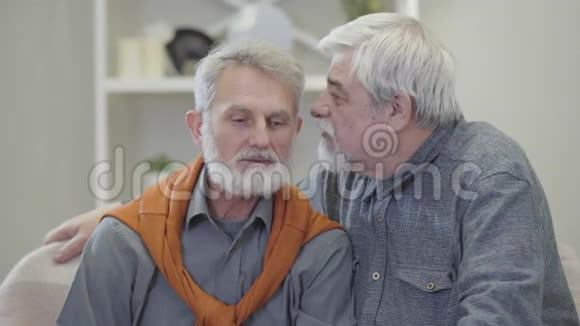 成熟白种人的特写镜头在朋友耳边低语笑话退休人员谈笑风生的画像视频的预览图
