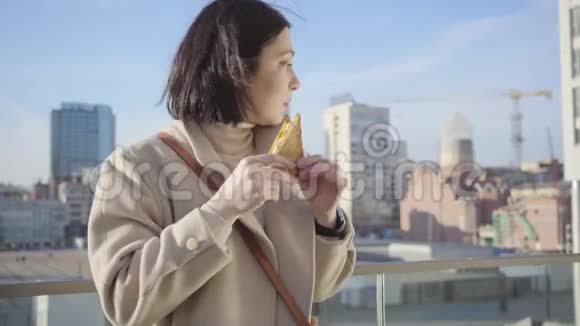 年轻的褐发白种人女人饿着肚子吃三明治的肖像一位成功的商务小姐在城市里休息视频的预览图