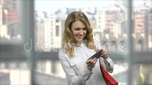 兴奋的年轻商务女性在她的智能手机上玩电子游戏视频的预览图