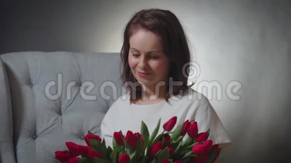 一位美女在椅子上闻着一束红色郁金香视频的预览图