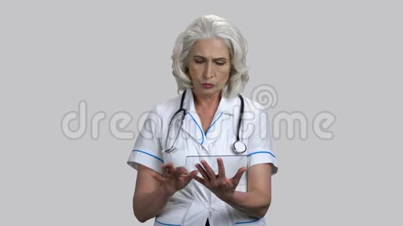 严重的高级女医生与玻璃模拟平板电脑设备视频的预览图