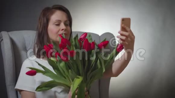美丽与一束红色郁金香在椅子上自拍视频的预览图