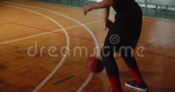 年轻的卷曲职业篮球运动员在玩球拍时把球扔进篮筐夜晚黑暗剪影视频的预览图