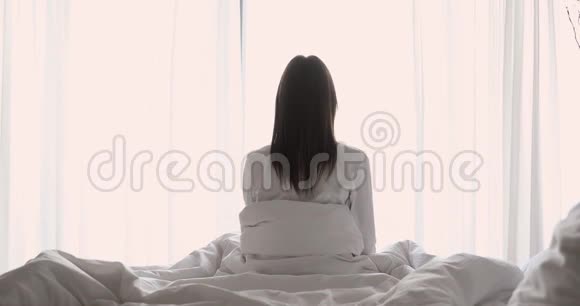 覆盖在毯子上的年轻黑发女人在早晨伸展视频的预览图