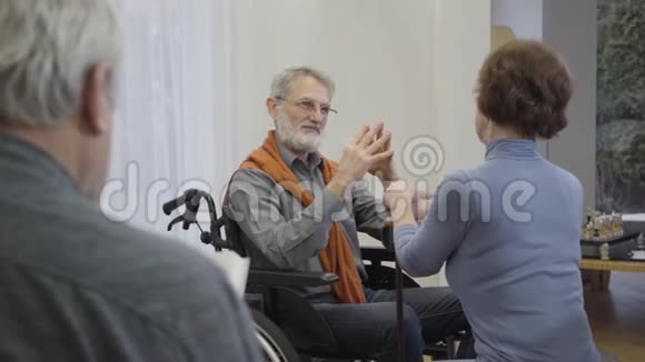 优雅的白种人老人坐在轮椅上手里握着一位年长的女人与女性调情的成熟退休者视频的预览图
