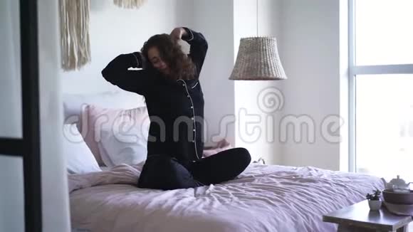 年轻女子在卧室里伸展美丽的白种人黑发女孩早上醒来的肖像视频的预览图