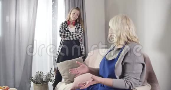 白人女性青少年与祖母争论讽刺的面部表情年轻女孩和金发女孩说话视频的预览图