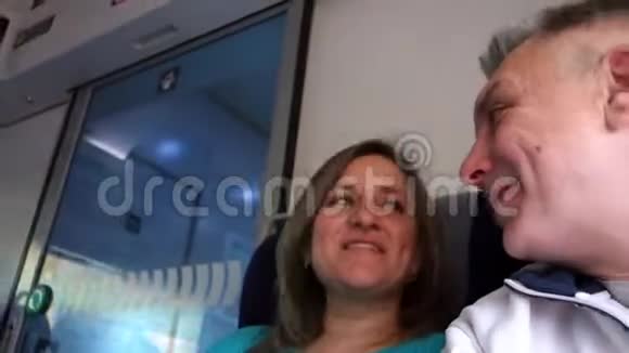 男人和女人在火车上说话几个中年人坐在公共交通铁路或地铁里微笑着说话视频的预览图