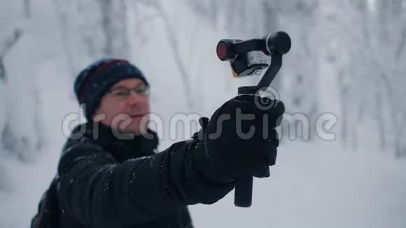 男子旅行者博客记录视频电影行动摄像头冬季森林视频的预览图