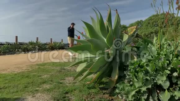 一个英俊的年轻人一个穿着海军蓝衬衫和短裤的男人正沿着加利福尼亚海岸圣克莱门特散步视频的预览图