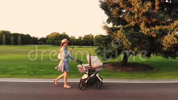 年轻的现代时尚妈妈带着婴儿车和电话视频的预览图