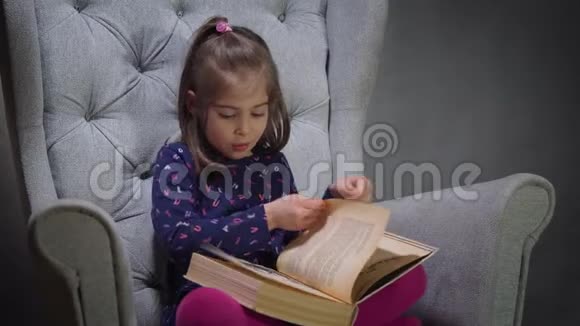 可爱的小女孩在椅子上看书视频的预览图