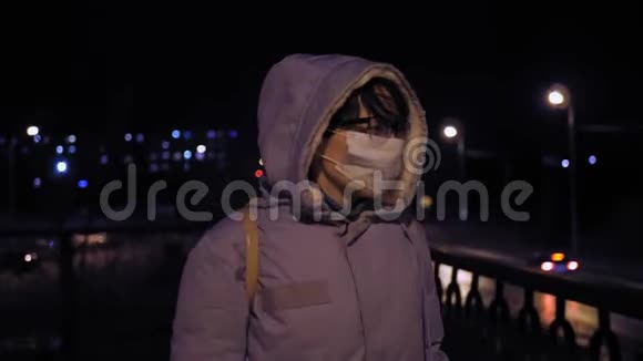 晚上街上戴防护面具的年轻女人的肖像视频的预览图