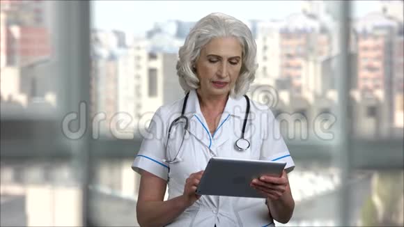 使用数字平板电脑的高级女医生肖像视频的预览图