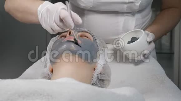 年轻漂亮的女人在美容院做手术年轻漂亮的女人躺在沙发上美容师面部护理视频的预览图