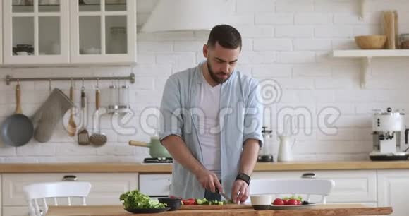 在家做饭的年轻人在厨房切菜色拉视频的预览图