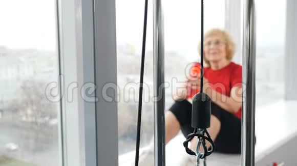 老年活跃的白种人妇女坐在窗台上在健身房训练后从瓶子里喝水退休妇女视频的预览图