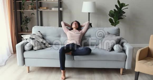 平静的年轻女士躺在客厅舒适的沙发上视频的预览图