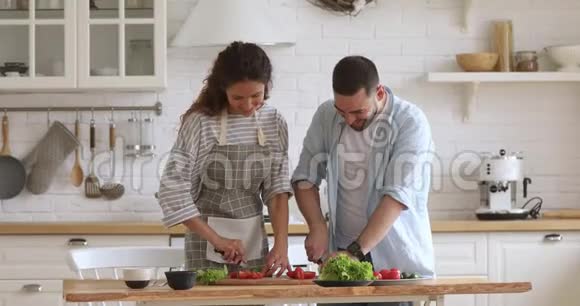 微笑的年轻夫妇切沙拉一起在厨房做饭视频的预览图