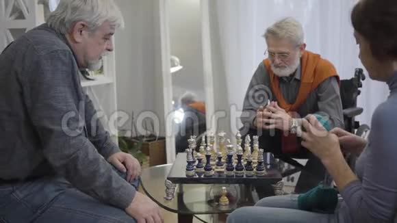 体贴的集中白人男子在疗养院下棋作为女人滚纱球成熟退休人员支出视频的预览图