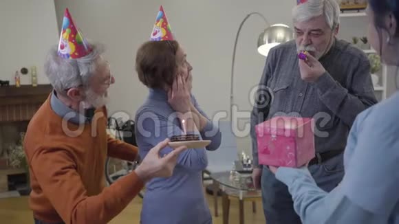 兴奋的老白种人女人在疗养院庆祝生日居民和志愿者吹党哨视频的预览图
