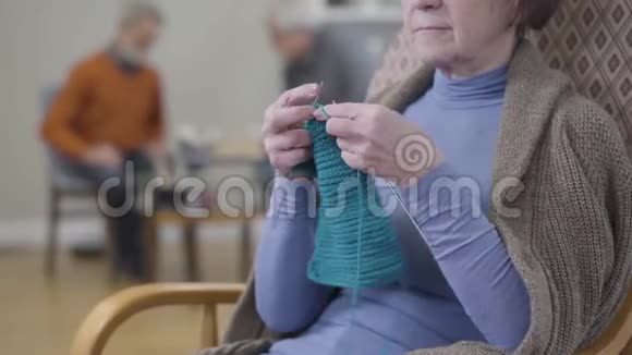 无法辨认的老高加索女人在扶手椅上编织成年退休人员在疗养院的空闲时间视频的预览图
