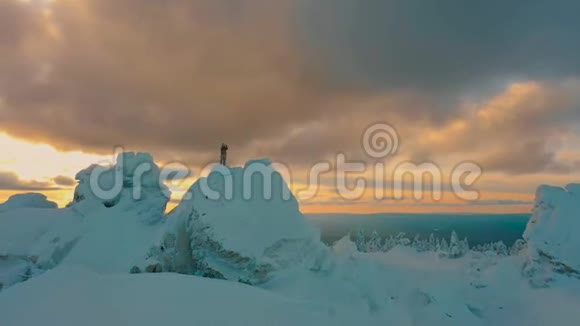 空中飞行徒步旅行者在冬季日落时站在雪山上拍照视频的预览图