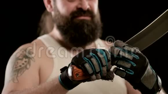 一个留着胡子的人戴着黑色工作室的手套手指沿着砍刀的刀刃视频的预览图