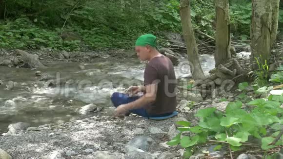 休息营地的游客在山间小溪里扔石头视频的预览图
