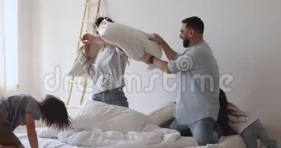 快乐的父母和小孩在床上打枕头仗视频的预览图