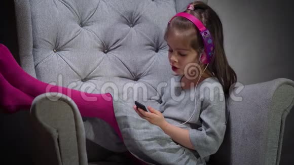 迷人的女孩在椅子上听音乐视频的预览图