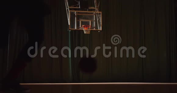 年轻的白种人卷发篮球运动员晚上在运动场的球拍上把球扔进篮筐视频的预览图
