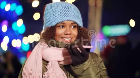 积极的黑人女孩晚上在假日市场上打电话视频的预览图