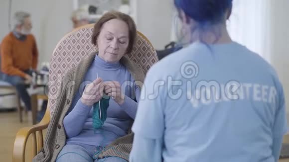 积极成熟的白种人妇女与无法辨认的志愿者在养老院交谈的肖像高级退休人员视频的预览图