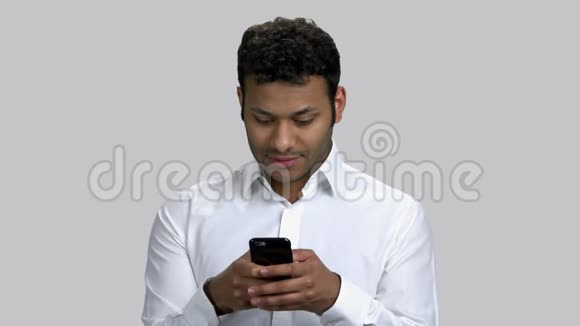 深色皮肤的年轻人在智能手机上输入信息的肖像视频的预览图