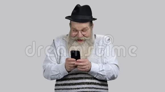 老年人在网上玩他的智能手机视频的预览图