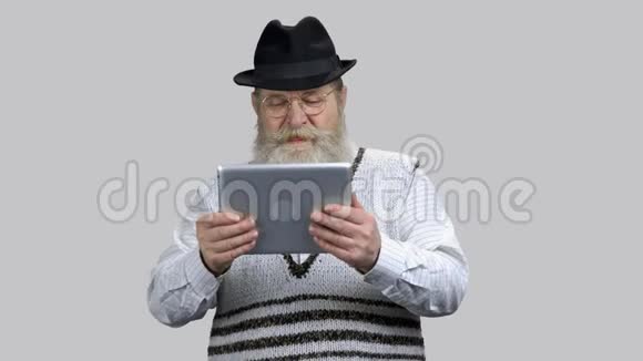老年退休男子在他的平板电脑上玩赛车游戏视频的预览图