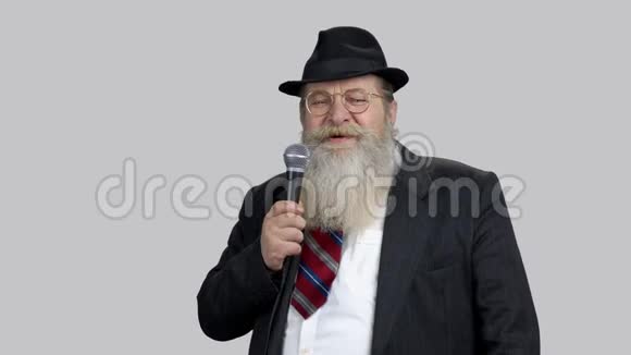 微笑的老高级演讲者留着长胡子用麦克风讲话视频的预览图