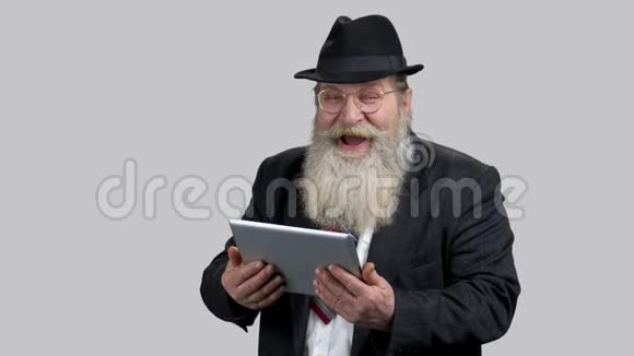 老资深商人在他的平板电脑上大笑着视频的预览图