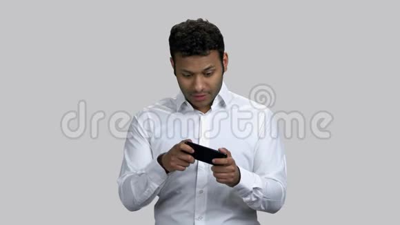 年轻的婴儿深色皮肤的男人在他的智能手机上玩电子游戏视频的预览图