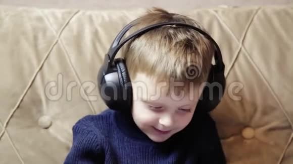一个带耳机的孩子一个微笑的孩子玩智能手机通过耳机听音乐一个特写镜头视频的预览图